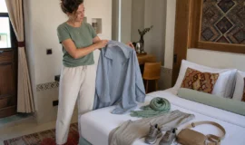 Female traveller packing a lightweight overshirt, trousers, scarf and walking shoes for Iran